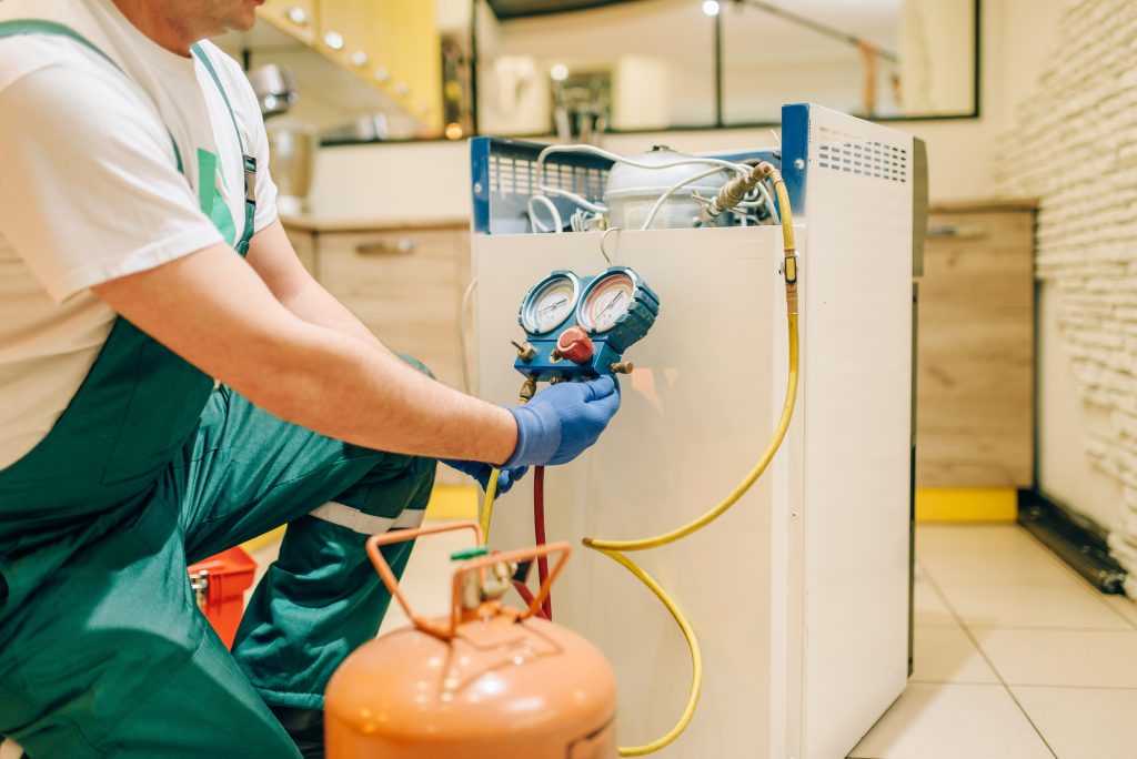 Worker in uniform fills compressor of refrigerator